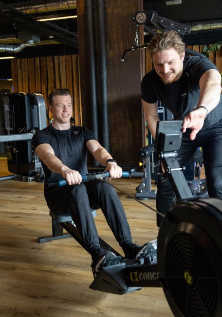 Twee collega's trainen op de roeimachine